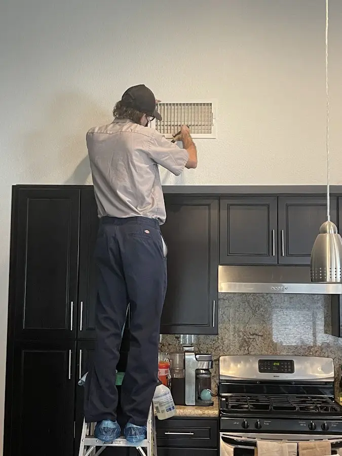Technician inspecting an air vent during HVAC service in Ballston